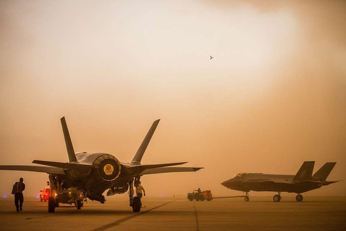 Two fighter jets on land in a yellow, smoggy background