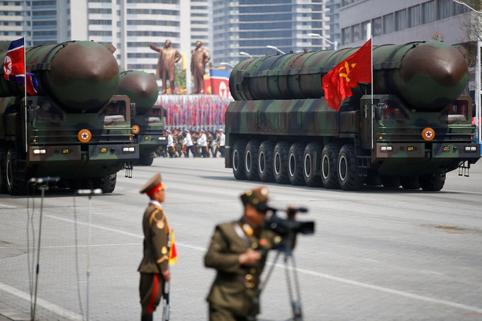Military vehicles carrying bombs drive down a street