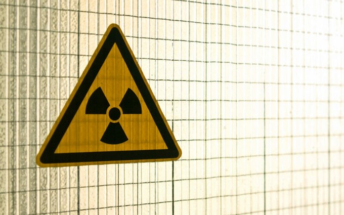 Yellow nuclear hazard sign on a cream background